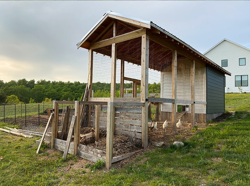 back of chicken coop with chicken run and compost bins