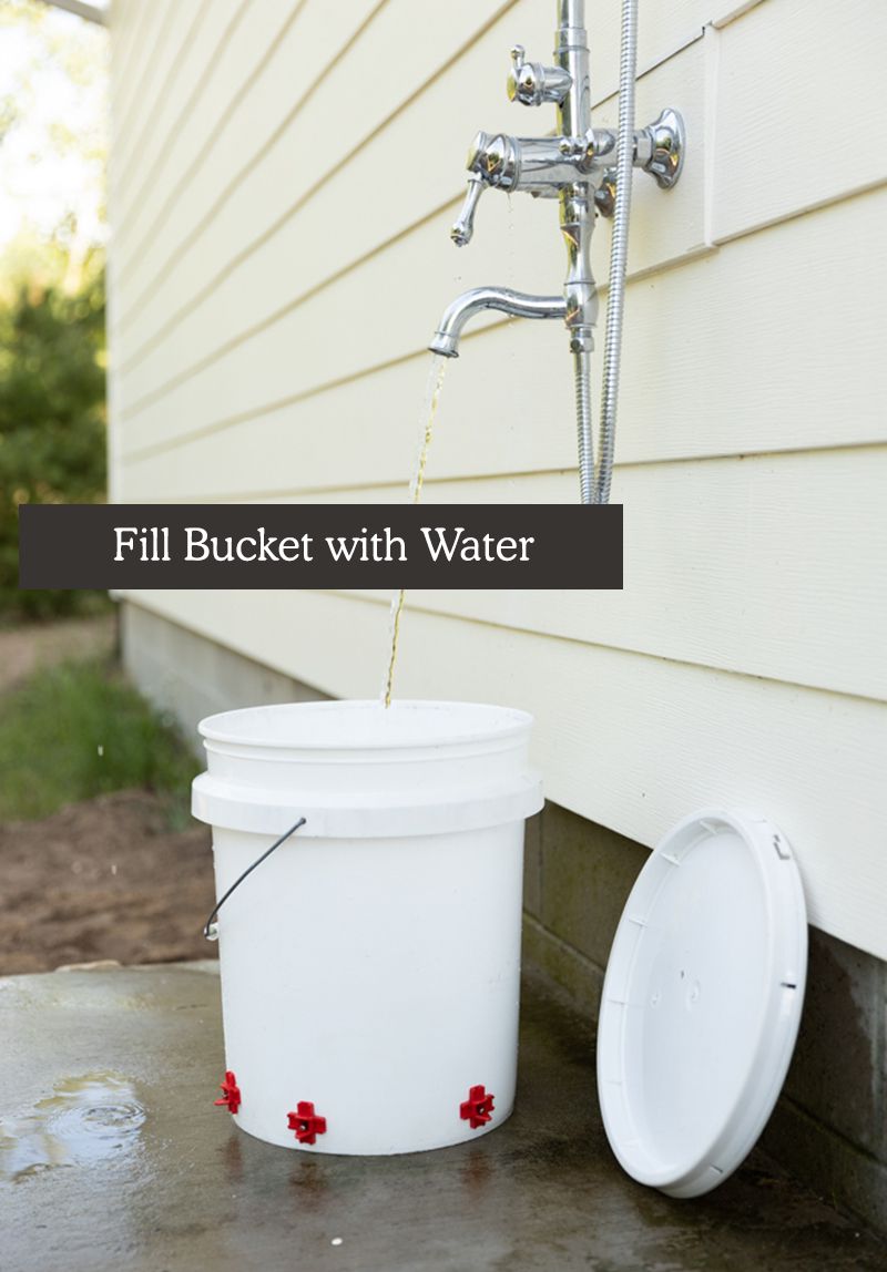 make your own chicken feeders - filling bucket with water