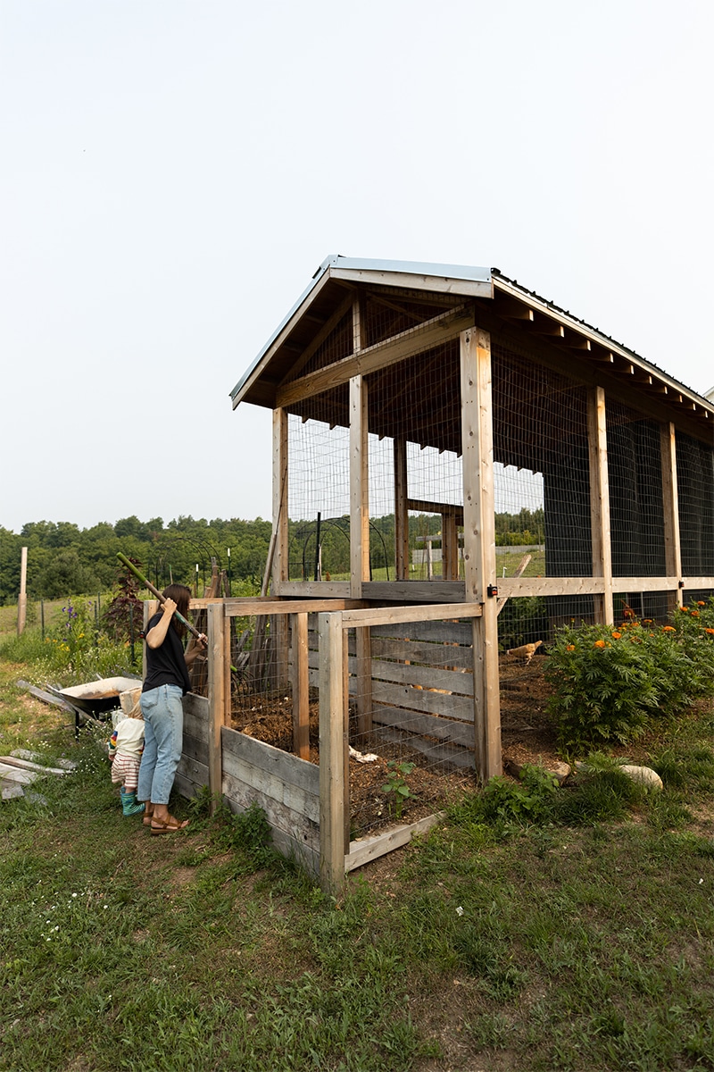 Woman turning a compost pile in a DIY Compost bin