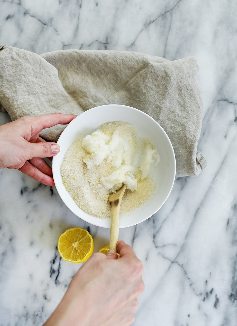 stirring the body scrub together in a bowl with all the ingredients for the DIY body scrub