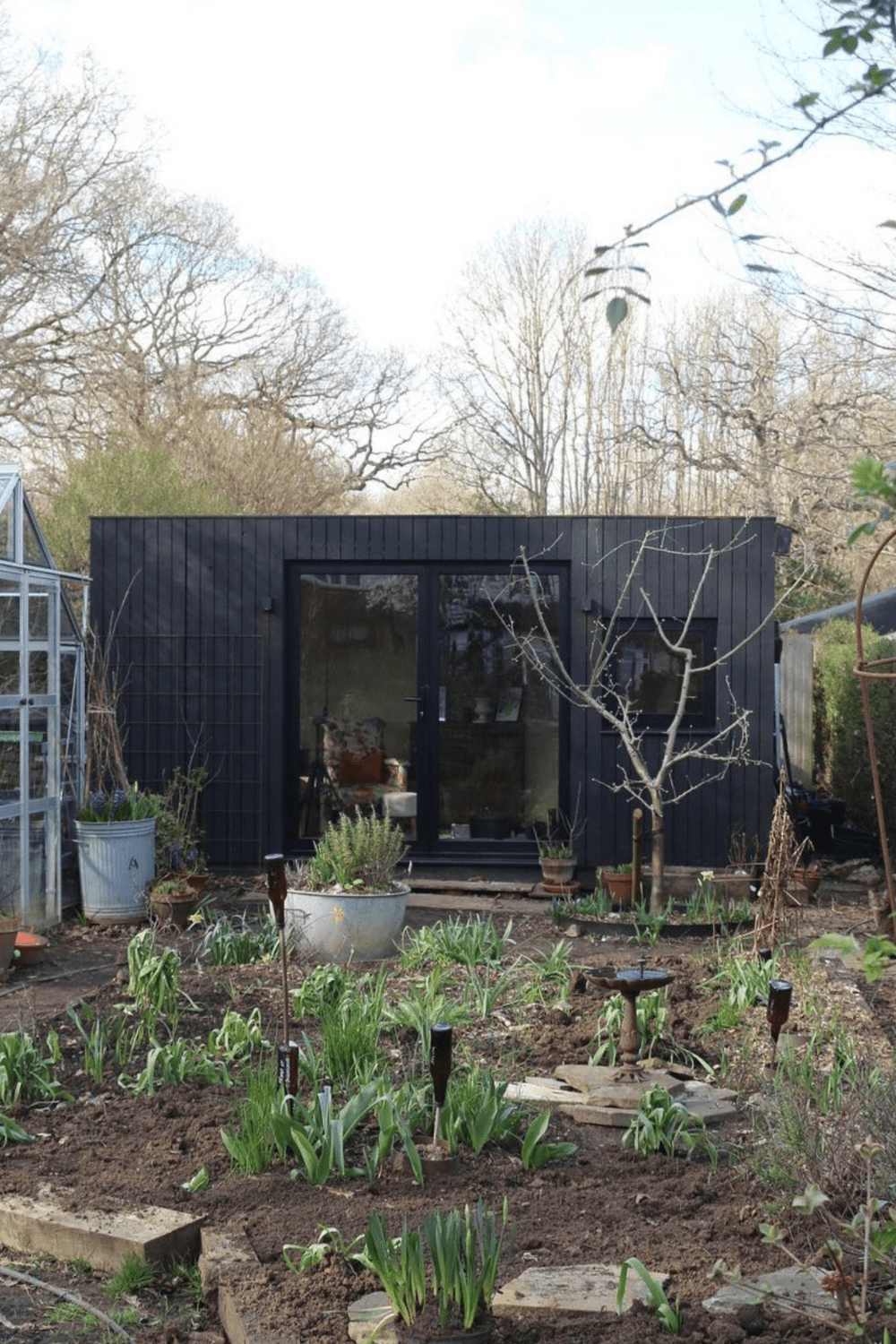 black modern shed in a garden with double glass windows